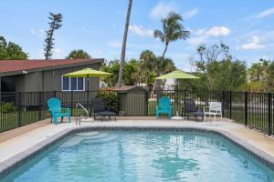 萨尼贝尔Renovated Cottage at the Historic Palms Inn of Sanibel- Includes Pool and Bikes的一个带蓝色椅子和遮阳伞的游泳池