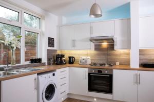 博格诺里吉斯Stunning 4br House for 10 Near Beach w Hot Tub的厨房配有白色橱柜、洗衣机和烘干机