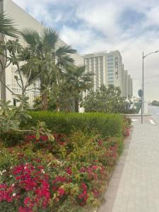 ‘Ūd al BayḑāʼApartmán Fiora, 2kk,Dubaj的一条种满鲜花和棕榈树的路边和建筑