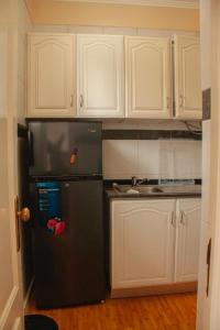 罗安达Studio 110的厨房配有黑冰箱和白色橱柜。