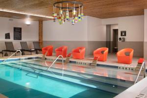 麦卡伦Aloft McAllen的一个带橙色椅子和吊灯的游泳池