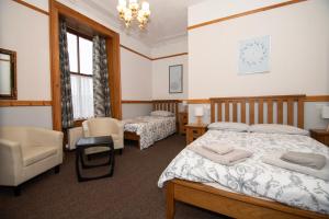 勒威克Alder Lodge Guest House的一间卧室配有两张床、椅子和吊灯。