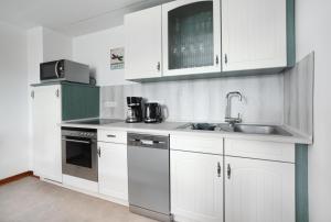 Hellenhahn-SchellenbergFerienwohnung Spatzennest的厨房配有白色橱柜和水槽