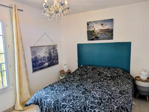 艾格-莫尔特Belle marina avec ponton et piscine collective的一间卧室配有蓝色的床和吊灯。