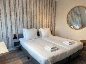 东卡佩勒Hello Zeeland - Appartement Duno Lodge M的卧室配有一张带镜子的白色大床