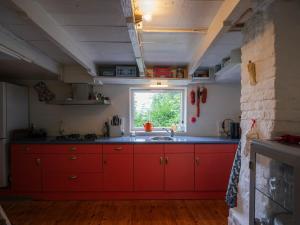 HengstdijkHello Zeeland - Vakantiewoning 't Schrijvershuisje的红色的厨房,配有水槽和窗户