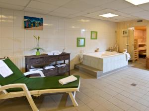 波鸿ACHAT Hotel Bochum Dortmund的带浴缸和绿色椅子的大浴室