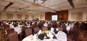 兰利海岸酒店&会议中心的宴会厅配有桌椅和屏幕
