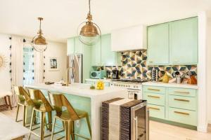 亚特兰大Penthouse Lux的一个带绿色橱柜的厨房和一个带椅子的厨房岛