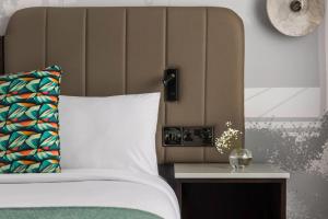 布兰察斯镇都柏林皇冠假日酒店布兰查的一张带白色枕头和边桌的床