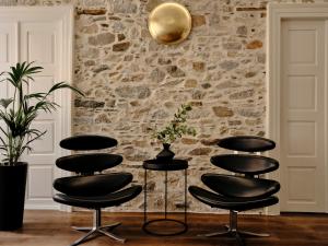 埃尔莫波利斯Argini Syros的一间设有黑色椅子和石墙的房间
