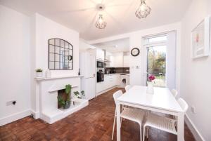 伦敦Lovely 2BR house in Norwood Junction London的白色的厨房配有桌子和壁炉