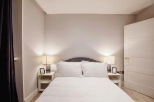伦敦Modern 2BR London Flat Style and Comfort Combined的一间卧室配有一张带两盏灯的大型白色床。