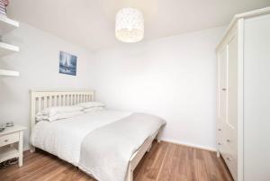 伦敦Charming 1BR flat with patio perfect for couples的卧室配有白色的床,铺有木地板