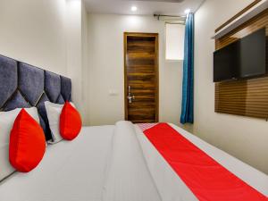 新德里OYO AR Residency的一间卧室配有一张带红色枕头的床和一台平面电视。