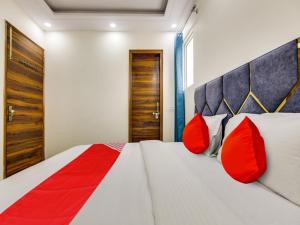 新德里OYO AR Residency的一间卧室配有一张带红色枕头的大床