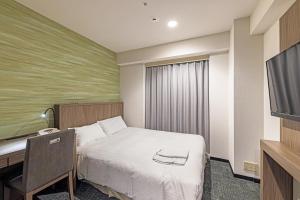 长野长野日航城市酒店的酒店客房配有一张床、一张书桌和一台电视。