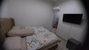 SukoharjoBELLA NINE EXCLUSIVE HOMESTAY的一间小卧室,配有一张床和一台平面电视