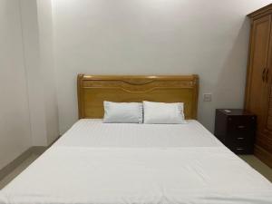 奠边府市502 Sân Bay Điện Biên的一张带木制床头板和两个白色枕头的床