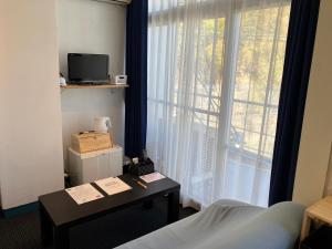 熊野市Oninosanpomichi的客房设有床、书桌和窗户。