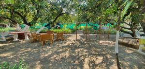 TalalaJadeshwarfarm&Resort的树下公园,公园里摆放着桌椅