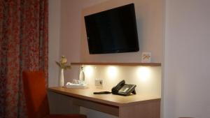 SchallbachHotel Garni Alte Post的酒店客房配有带电话的书桌和电视。