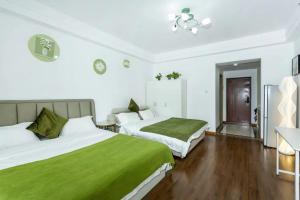 大连大连红熙缘酒店式公寓万达广场店的酒店客房,配有两张带绿床单的床