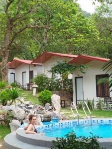 吉婆岛Tran Chau Garden Home的坐在房子前的游泳池里的孩子