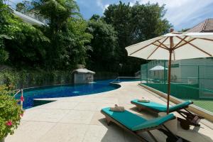 卡塔海滩Katamanda villa Sooksan的一个带2把躺椅和遮阳伞的游泳池