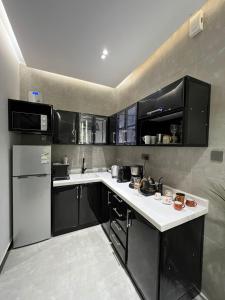 哈伊勒DESERT ROSES 2的厨房配有黑色橱柜和白色台面