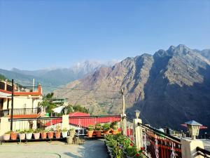 乔斯希马特Hotel Joshimath Inn的一座有栅栏和山脉背景的建筑