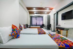纳西克FabHotel Priya Lodging, near Ojhar Airport的酒店客房设有两张床和电视。