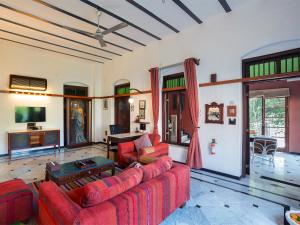 艾哈迈达巴德The House of MG-A Heritage Hotel, Ahmedabad的客厅配有红色沙发和电视
