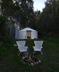 EikažiGlamping Yurt Purvs at Kleja Quiet Camping的院子里有两把椅子和火,有帐篷
