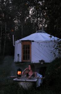 EikažiGlamping Yurt Purvs at Kleja Quiet Camping的坐在帐篷前的床上的女人