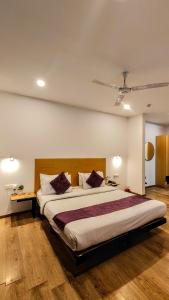 古尔冈Mavens White Artemis Hospital Road Sector 52 Gurgaon的一间卧室配有一张带紫色枕头的大床