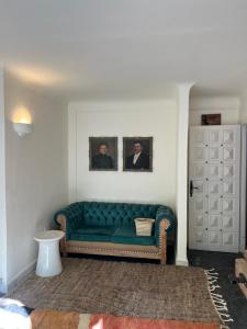 马拉喀什MORO Marrakech Boutique Hôtel的客厅里一张绿色的沙发,墙上挂着两张照片