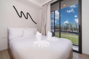 普吉镇Laguna BangTao Beach skypark Apartment的卧室配有白色的床和大窗户