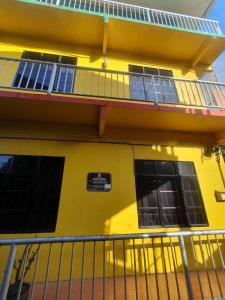 Kampong Pasir HantuJV Inn Perhentian的黄色的建筑,设有窗户和阳台