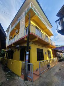 Kampong Pasir HantuJV Inn Perhentian的黄色的建筑,上面设有阳台