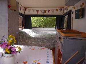 Pleumeur-GautierBretagne Chambre d'hôtes suite 53m2 et Caravane vintage avec cuisine et salle de bains privées Brittany B&B 53m2 suite and Vintage caravan glamping with private kitchen and bathroom的露营车,设有厨房和带鲜花的桌子