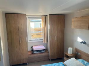 雷日卡普费雷Mobil home climatisé au calme et proche des activités LEGE CAP FERRET的一间卧室设有木制橱柜和窗户。