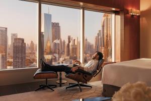 迪拜朱美拉阿联酋塔酒店的坐在酒店带窗户的房间里椅子上的男人