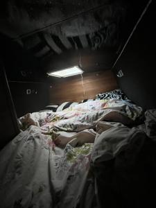 曼彻斯特Waterside campervan的两个孩子躺在黑暗的房间里的床上