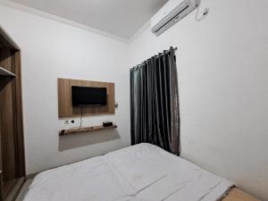 井里汶OYO 93870 Damai Guest House Cirebon的一间卧室配有一张床和一台平面电视