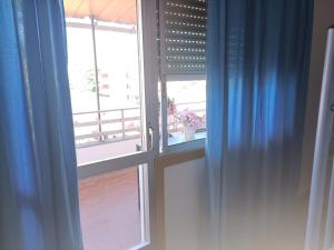 雷东德拉Pilgrim Rooms的客房内的开放式窗户配有蓝色窗帘