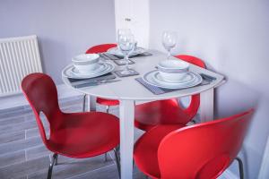 SpittalBeach House in Berwick Upon Tweed - 2 Double Bedrooms的白色桌子、红椅子和酒杯