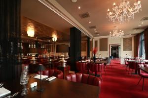 不来梅港哈佛坎普酒店的餐厅设有红色的桌椅和吊灯