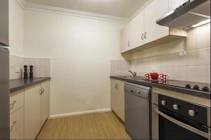 珀斯Narnia in Northbridge - One Bedroom的厨房配有白色橱柜和炉灶烤箱。