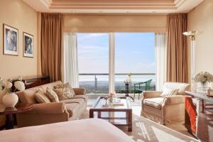 塞萨洛尼基帕诺拉玛酒店的带沙发和椅子的客厅以及大窗户。